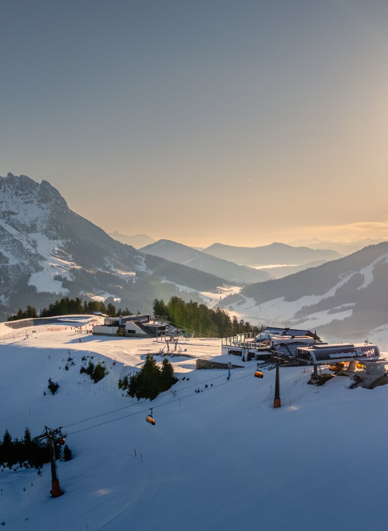 Snow-covered ski area at Hochkönig with lifts, gondolas and mountain station in bright morning sunlight | © Hochkönig Bergbahnen GmbH