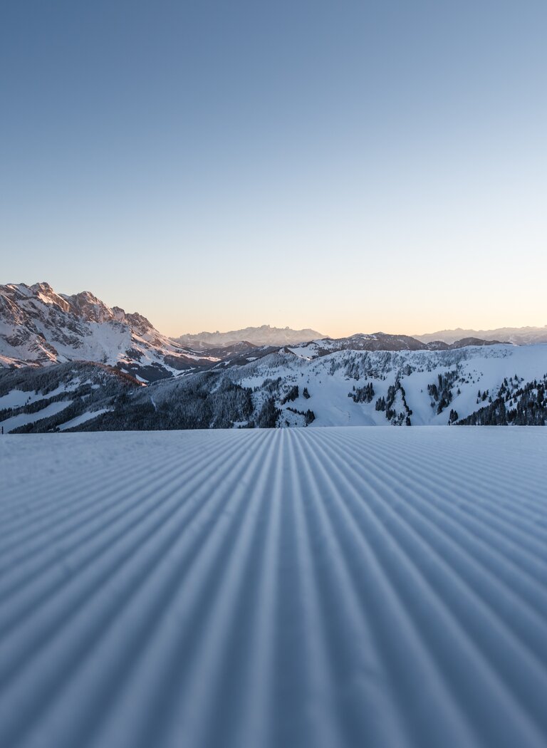 Freshly groomed slope at sunrise with view of the snowy Hochkönig massif and expansive mountain landscape | © Hochkönig Tourismus GmbH