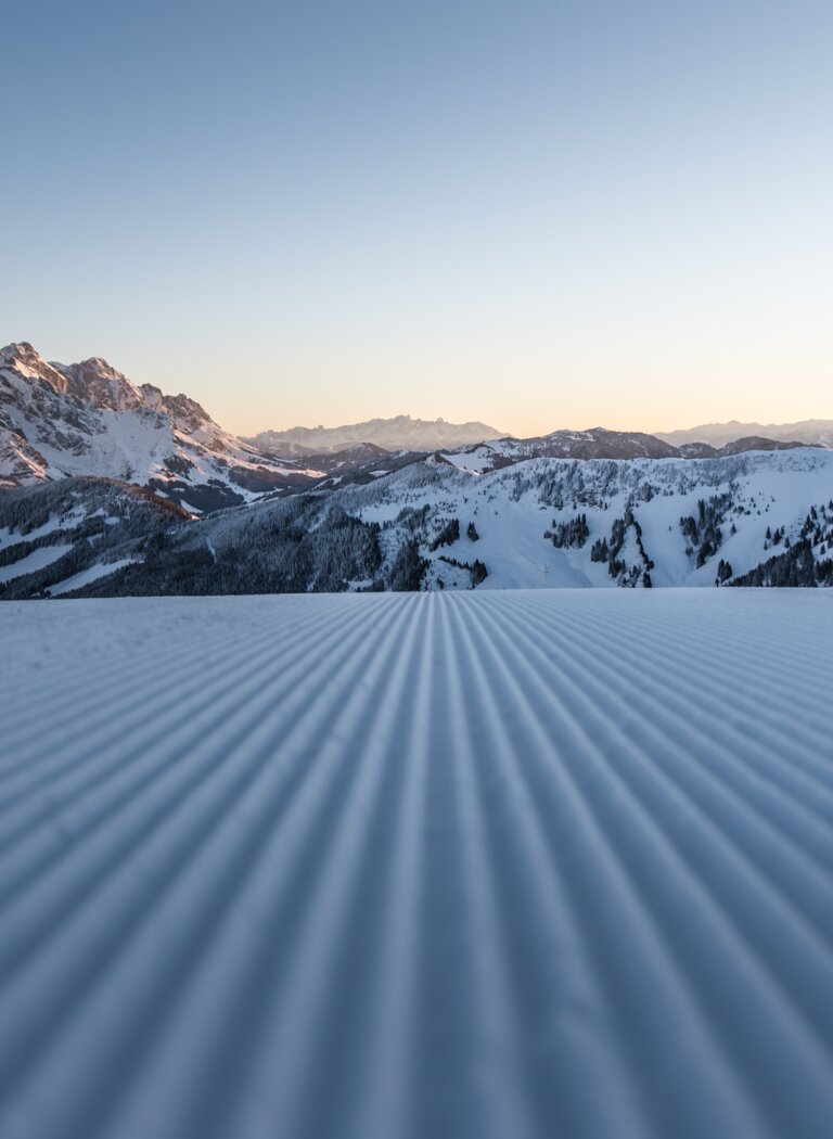 Freshly groomed slope at sunrise with view of the snowy Hochkönig massif and expansive mountain landscape | © Hochkönig Tourismus GmbH