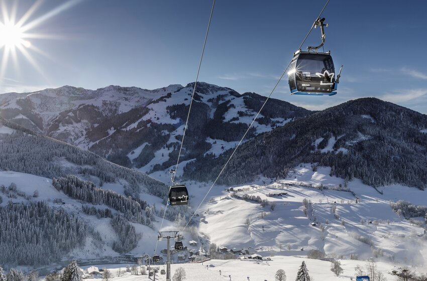 Sonnbergbahn gondolas float in sunshine above snowy slopes in the Hochkönig ski area. | © Hochkönig Bergbahnen GmbH
