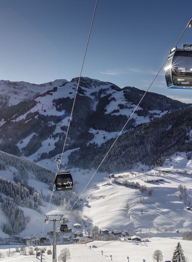 Sonnbergbahn gondolas float in sunshine above snowy slopes in the Hochkönig ski area. | © Hochkönig Bergbahnen GmbH